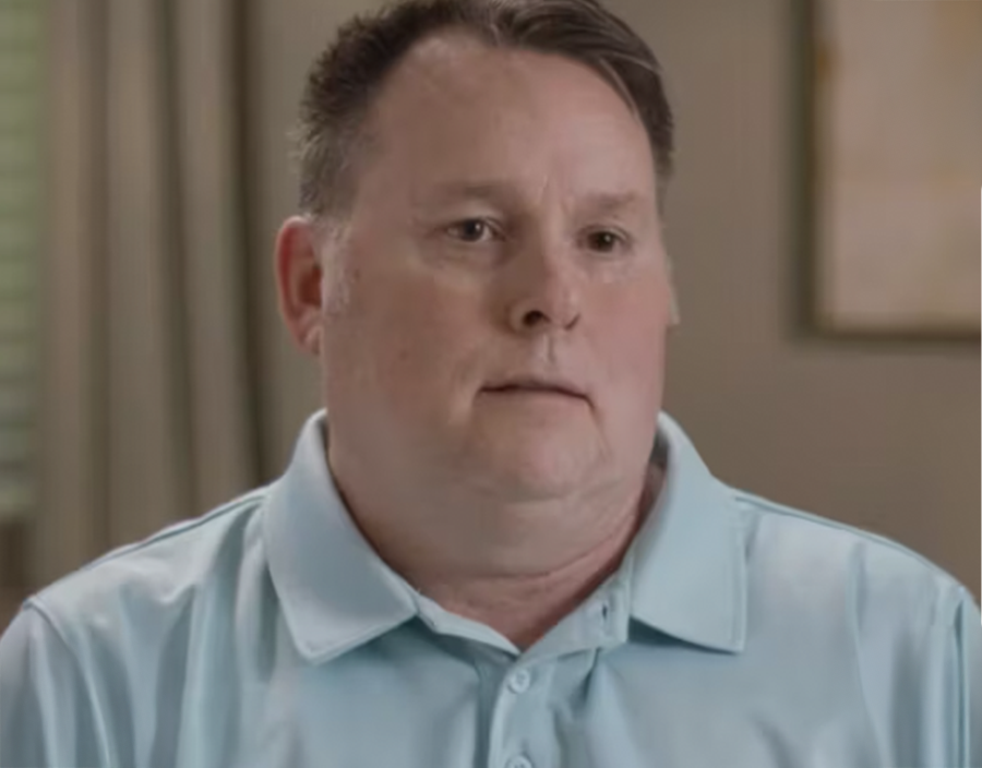 Joseph, a stroke survivor man with short dark hair wearing a light blue polo shirt, sitting indoors in a softly lit room, looking slightly to the side, giving his Vivistim testimonial