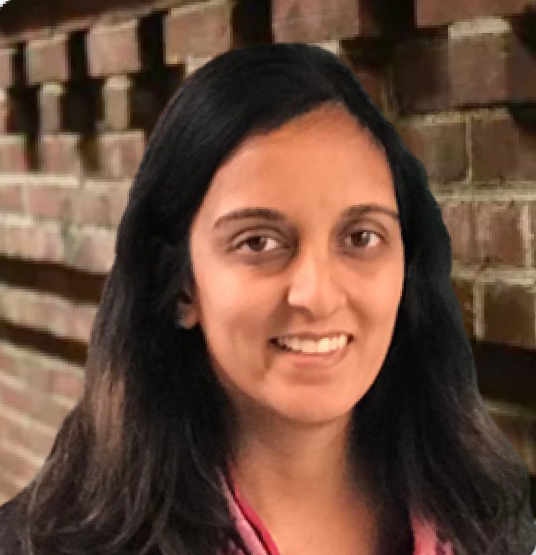 Portrait of a woman with long dark hair standing in front of a brick wall